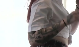 Una ragazza rossa dai capelli rossi mostra i suoi tatuaggi